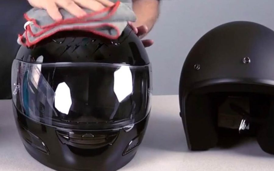 Una mano limpia un casco negro con una franela
