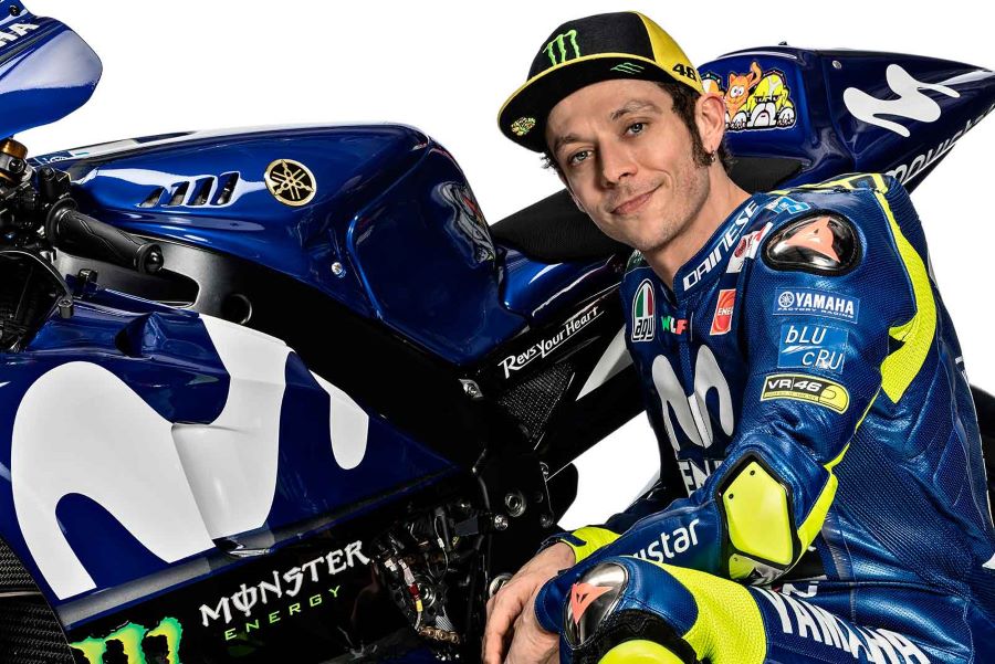 Valentino Rossi en cuclillas al lado de una moto Yamaha de MotoGP