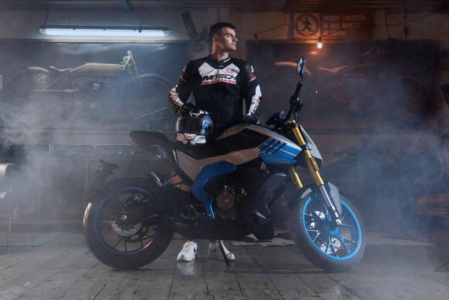 FB Mondial Piega 125: la naked sensación en Europa Un piloto sostiene su casco sobre el asiento de la FB Mondial Piega 125, en un entorno oscuro y lleno de humo o niebla