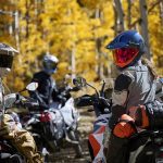 Diez novedades de cascos de moto premium 2025 Un grupo de motociclistas sobre sus monturas miran hacia atrás con los cascos puestos