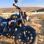 Una Kewway Superlight negra parada detrás de una valla blanca a un costado de la ruta de una zona campestre