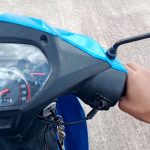 Cómo manejar una moto 110: guía para iniciarse Una mano agarra el puño recho de una moto CUB 110 celeste