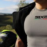 Ropa de moto de verano: prendas para no pasar calor Un motociclista con la chaqueta abierta muestra una camiseta de moto de verano gris de la marca Six2