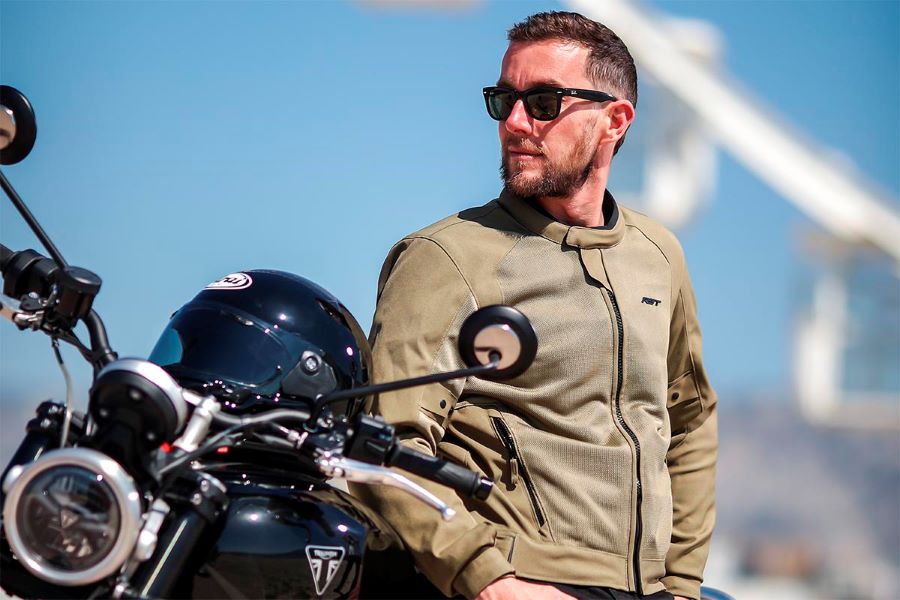 Un usuario de la chaqueta RTS Spectre Air 2 se apoya en su moto mientras mira al horizonte