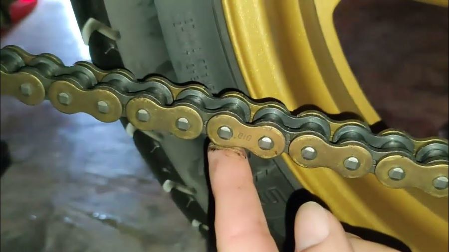 Un mecánico revisa la tensión de la cadena de una moto