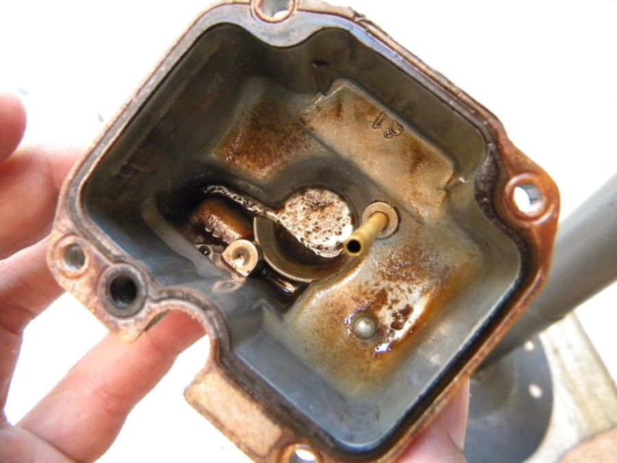 Interior de la base de un carburador de moto llena de óxido