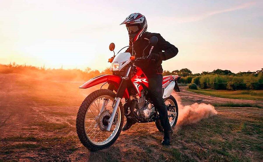 una Honda CB250 Tornado roja a punto de salir rauda por la tierra