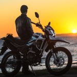 Nuevas Zanella ZR: la gama estrena tecnología y seguridad Un motociclista se apoya sobre su Zanella ZR 150 para observar el amanecer