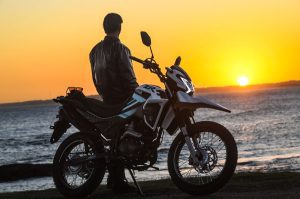 Un motociclista se apoya sobre su Zanella ZR 150 para observar el amanecer