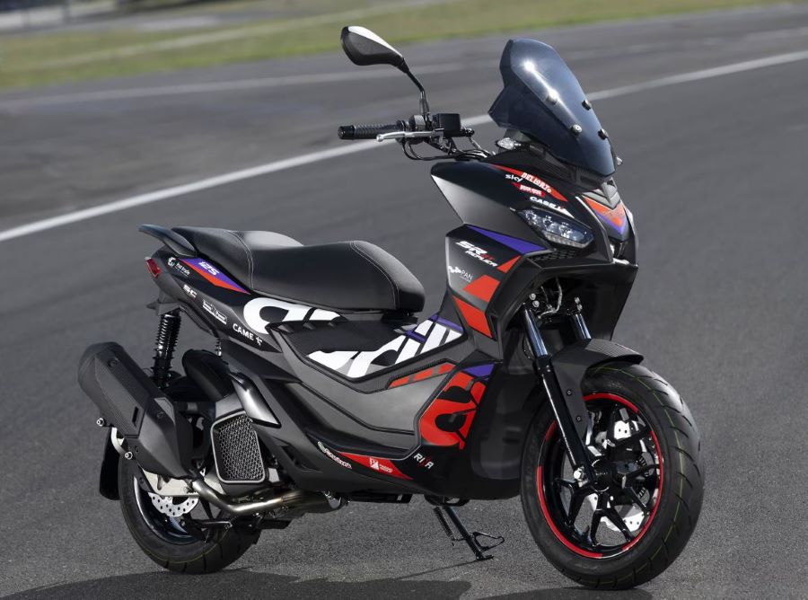 Un scooter Aprilia SR GT 125 negro con detalles rojos y blancos esatacionado en una pista.