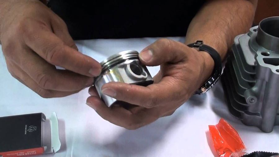 Un mecánico sostiene en sus manos un pistón de moto