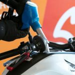 ¿Qué gasolina es mejor para una moto? Guía simple y útil Una manguera de surtidor carga combustible en una moto blanca