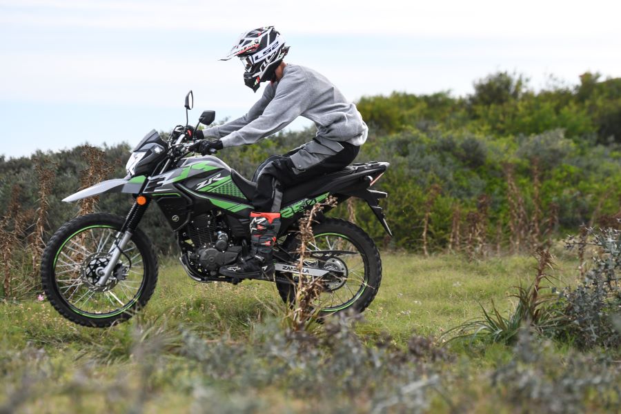 Una Zanella ZR 250 verde salta una lomada de un terreno campestre