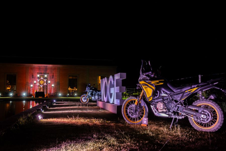 Una VOGE DS800X Rally amarilla se luce en plena noche y con luces ténues al lado de la leyenda VOGE en letras corpóreas