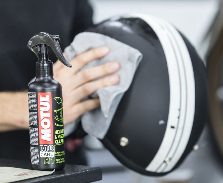 Un usuario se apresta a limpiar un casco con un producto en aerosol