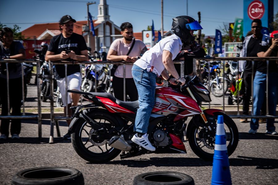 Un motociclista se para sobre los pedalines de una moto deportiva roja durante una jornada de Bajaj