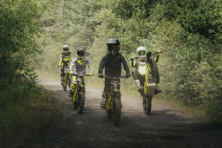 Motos eléctricas todoterreno Triumph TXP para jóvenes Cuaro jóvenes avanzan por un sendero con su modelos Triumph TXP
