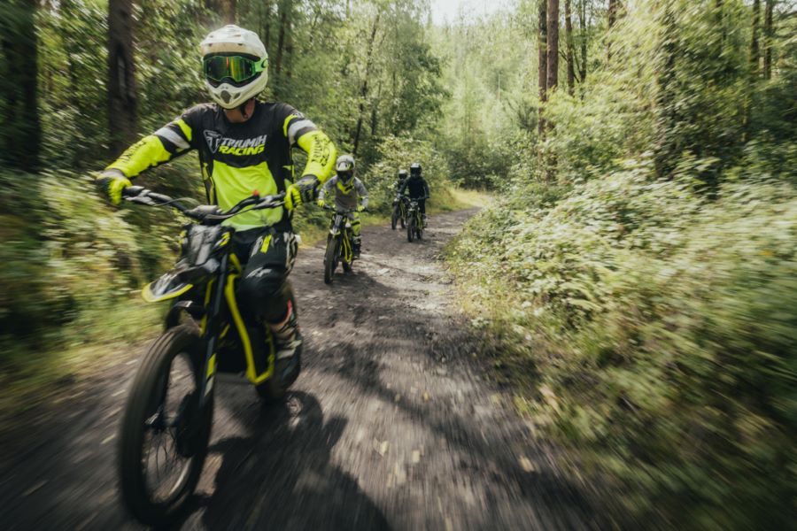 Motos eléctricas todoterreno Triumph TXP para jóvenes un adolescente avaza en una Triumph TXP 26 eléctrica por un sendero