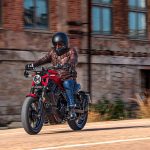 Un usuario se desplaza por una zona de la ciudad con edificios en ruinas con una Zontes 125C roja