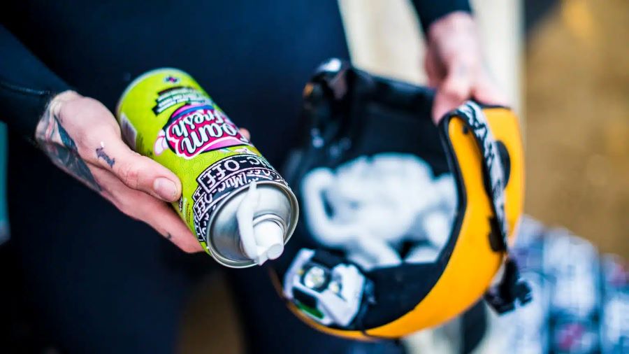 Un usuario se apresta a limpiar un casco con un producto en aerosol