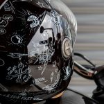 Un casco de moto negro totalmente cubierto de pegatinas con motivos temáticos
