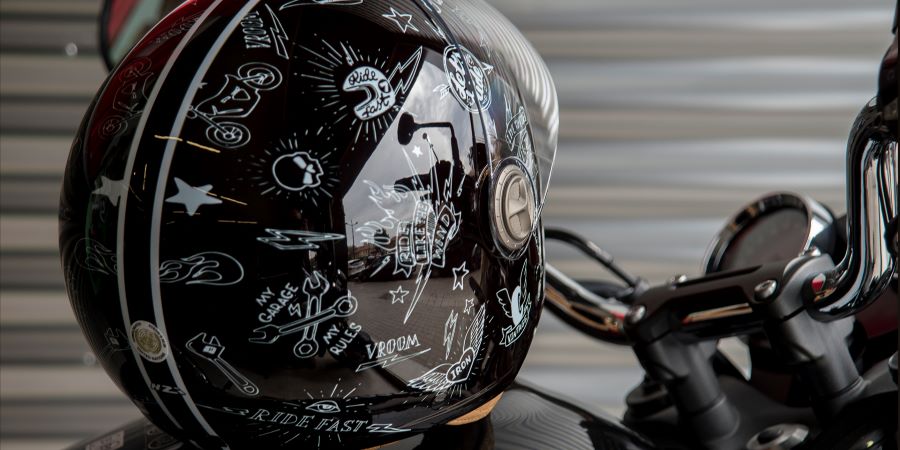 Un casco de moto negro totalmente cubierto de pegatinas con motivos temáticos