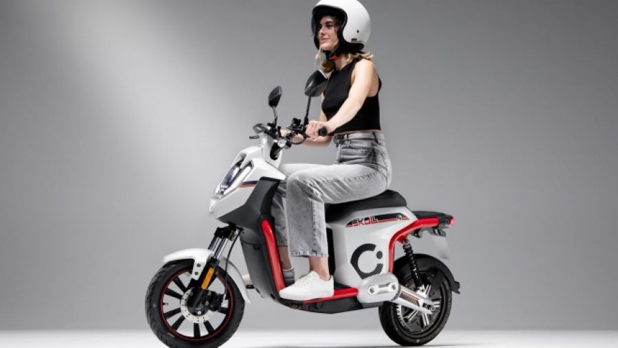 Una modelo joven posa sobre un scooter eléctrico Cecotec Skull blanco y rojo