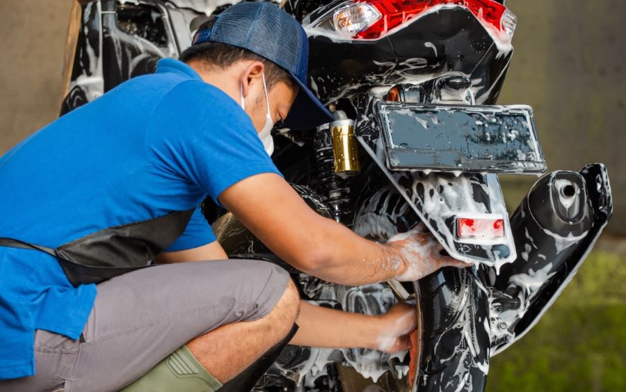 Una persona con barbijo lava una moto