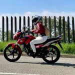 Una mujer se desplaza con una Honda CB125F roja por una calle