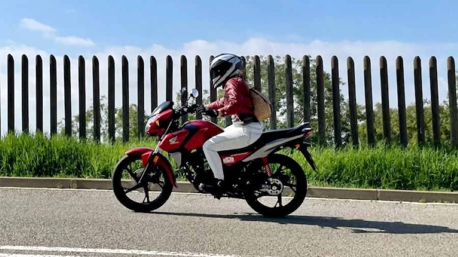 Una mujer se desplaza con una Honda CB125F roja por una calle
