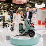 Un directivo de Lambretta y dos modelos vestidas de blanco posan junto a la nueva Lambretta Elettra S en el EICMA 2025