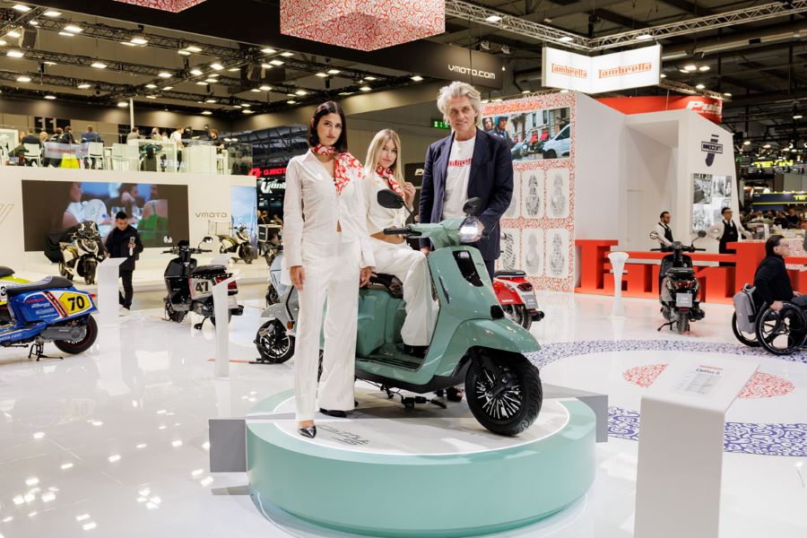Lambretta Elettra S y J: futuro eléctrico y estilo retro Un directivo de Lambretta y dos modelos vestidas de blanco posan junto a la nueva Lambretta Elettra S en el EICMA 2025