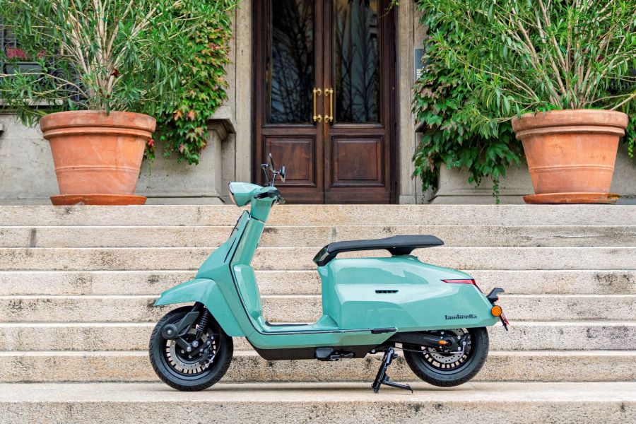 Lambretta Elettra S y J: futuro eléctrico y estilo retro Lateral izquierdo de una lambretta Elettra S verde sobre las escalinatas de acceso de una mansión