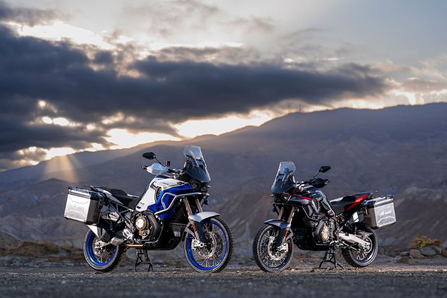 Una MV Agusta Enduro Veloce blanca y otra negra posan sobre un terreno montañoso con un cielo tormentoso de fondo