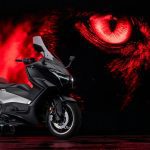 Un Yamaha TMAX 25 aniversario posa con un fondo de ojo felino rojo