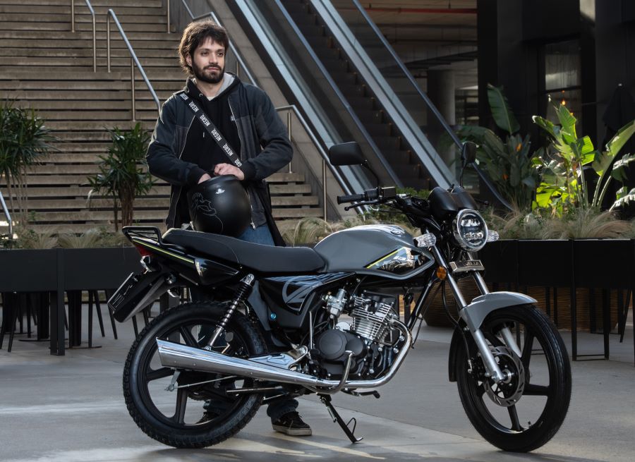 Un usuario, casco en mano, se dispone a subir a su moto Zanella RX 150 Full gris