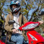 Un usuario con casco sentado sobre una moto Corven Energy 110 roja