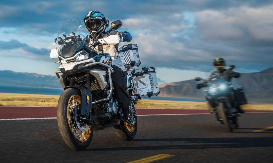 Una moto CFMoto 700MT azul y blanca encabeza un desplazamiento por carretra