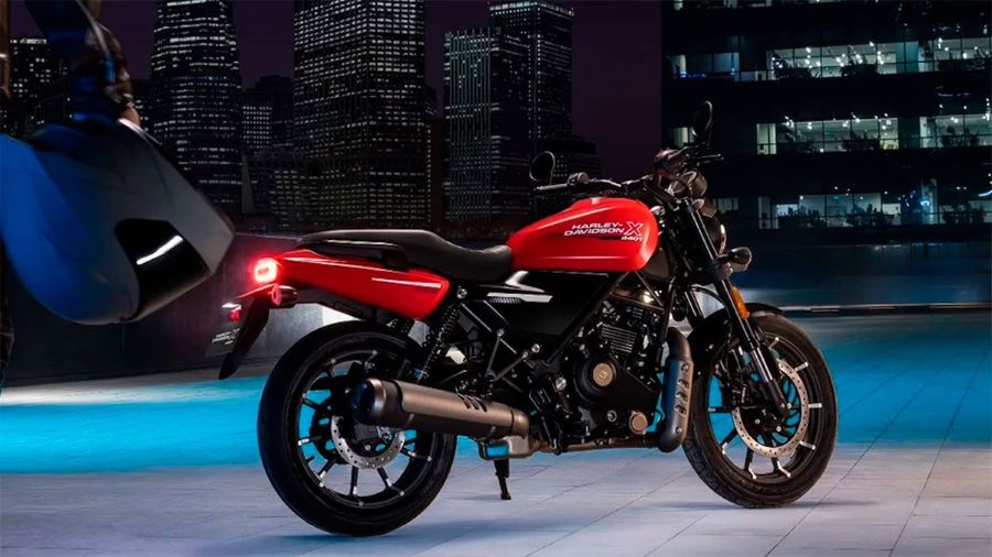 Una Harley-Davidson X440 T roja posa con una ciudad nocturna de fondo