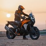 En medio de un atardecer, un piloto descansa sobre su KTM 1390 SUPER ADVENTURE S EVO