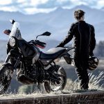 Un piloto mira el paisaje montañoso al lado de una moto Motori RTZ 500