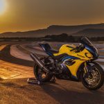 Una moto Suzuki GSX-R1000 2026 amarilla parada al borde de una pista en un amanecer