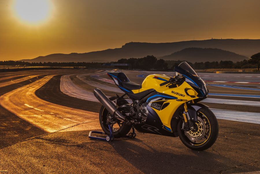 Una moto Suzuki GSX-R1000 2026 amarilla parada al borde de una pista en un amanecer