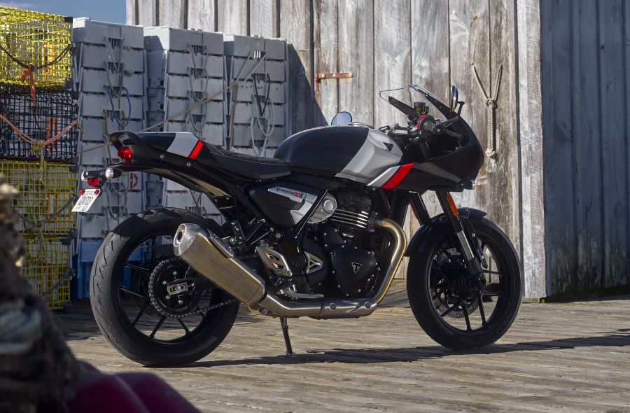 Por qué las Tracker 400 y Thruxton 400 son clave para Triumph Una moto Triumph Thruxton 400 negra parada en un contexto portuario