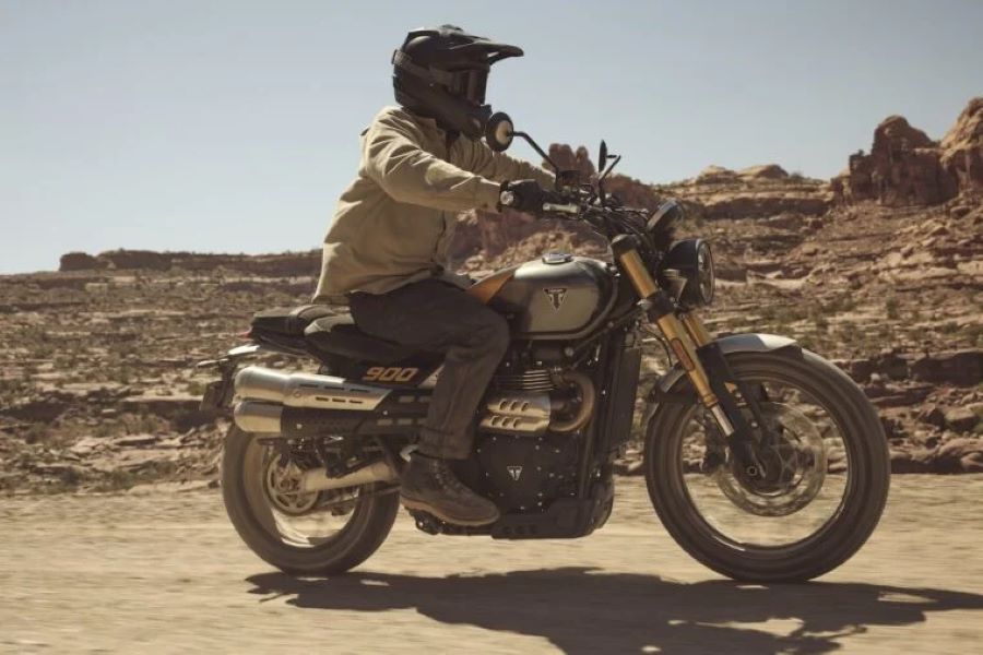 Una moto Triumph Scrambler 900 2026 se desplaza por una ruta de tierra desértica