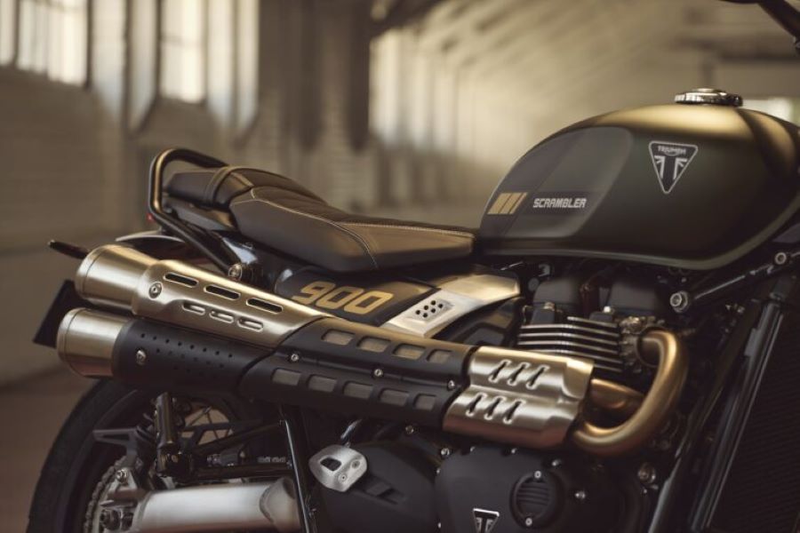 Triumph renueva la Scrambler 900 sin sacrificar su alma clásica Vista parcial del tanque, la parte de ciclo y los escapes de una moto Triumph Scrambler 900 2026