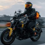 Letbe Arthur 700: una nueva lectura del estilo neo-retro Un piloto se desplaza por una ruta a bordo de una moto neo-retro Letbe Arthur 700 gris con detalles amarillos