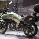 La Norton Atlas define el verdadero regreso de la marca Vista lateral izquierda de una moto Norton Atlas verde con maletas expuesta en un stand