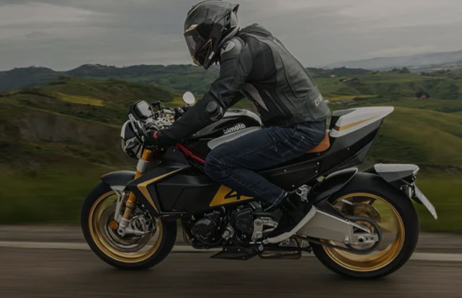 Una moto Bimota KB4 RC blanca con llantas doradas viaja a gran velocidad por una ruta