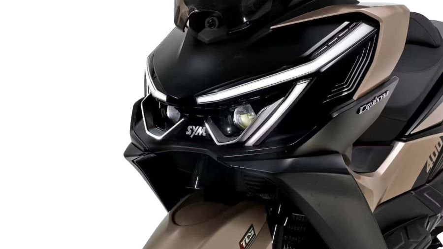 frotal de un scooter SYM Cruisym 400 marrón con las luces de día encendidas